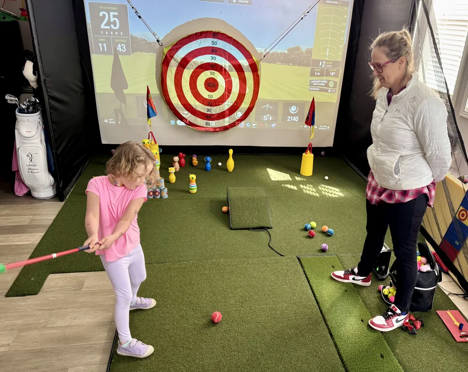 A young golfer taking part in an indoor golf activity.